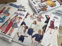 Assorted clothing sewing patterns including dresses, blouses, and skirts shown in multiple vintage illustrated designs on envelopes.