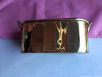 Side view of polished small brass flower planter showing smooth reflective surface and handle detail