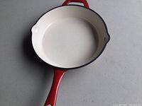 Red Tramontina frying skillet with cream interior, view showing entire skillet and handle