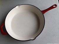 Top view showing white enamel interior and red handles of the frying pan.