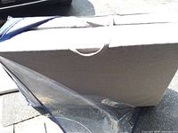 Folded tri-fold mattress inside navy fabric carrying case with clear plastic flap and handle exposed.