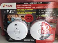 Packaging front showing two white round Kidde smoke alarms with sealed lithium batteries and talking vocal feature.
