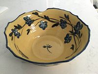 Top view showing glossy yellow interior with hand-painted blue flowers and a blue dragonfly at center