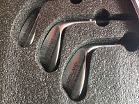 Three Kirkland branded golf wedges arranged in foam packaging showing club faces.