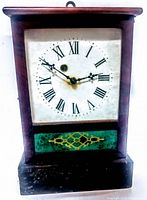 Front view of antique wooden wall clock showing Roman numeral dial, clock hands, and decorative bottom panel