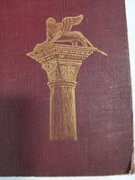 Close-up of the gold embossed winged lion on a classical column on the book's front cover illustrating the decorative detail.