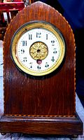Full view of the antique wooden mantel clock with marquetry detail and pointed arch top.