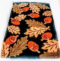 Full view of vintage crewel area rug with acorns and oak leaves on black background