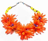 Close-up photo showing five bright orange lucite floral clusters with purple bead centers arranged on necklace.