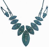 Front view of the necklace and earrings set laid flat showing emerald green rhinestone leaf-shaped segments