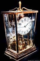 Angled front side view of the vintage brass carriage clock with etched glass panels, showing detailed floral etching on the side glass and white clock face with black numerals and red accents.