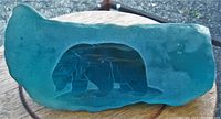 Full side view of aqua glass sculpture showing iceberg shape and etched polar bear inside.
