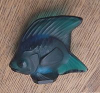 Top view of aqua blue Lalique crystal fish figurine on wood surface showing front fin, eye and body texture.