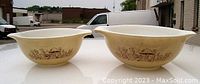 Pair of vintage Pyrex mixing bowls with mushroom design in mocha colors, shown side by side from top front angle.