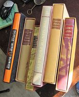 Top view of six hardcover classic books in slipcases, showing titles and varying colors of cases including orange, beige, brown, gold, and maroon.