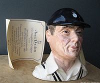 Front view of the Royal Doulton Toby Jug with certificate showing the detailed face and cricket cap.
