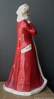Side view of the vintage Royal Doulton porcelain figurine showing the glossy red coat with white fur trim and the white fur hat.
