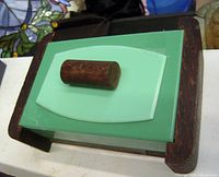 Top angled view of Art Deco jade green glass jewelry box closed showing wood frame and wooden knob on lid.