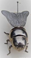 Top front angle photo showing detailed silver plated bee head, legs, and open wings revealing glass body.