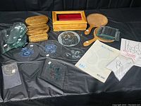 Overall lot showing clear bevel glass panels, wooden bases, hand mirrors, and decorative stencils on a black background