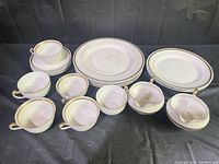 Full view of collection including plates, tea cups, and sauce boats with gold trim detailing on white porcelain.