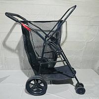 Side view of the black folding beach cart with mesh storage compartment and foam grip handle