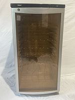 Front view of Haier wine cooler showing transparent door with metal racks inside and gray frame