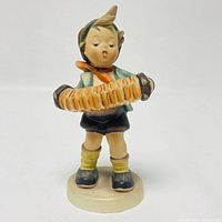 Front view of the Hummel girl figurine holding an accordion, showing detailed facial expression and outfit colors.