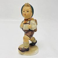 Front and side views of the Hummel School Boy figurine showing details of the painted finish, facial expression, and outfit