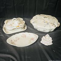 All four pieces together: two covered casseroles/platter sets, a floral serving platter, and a small decorative dish.