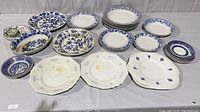 Overview of all blue and white plates and serving dishes, showing variety of sizes and patterns including floral and bird motifs.