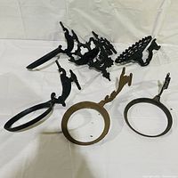 Photo of six vintage metal wall sconce accessories: rings and holders in various designs and colors, some black metal, one brass-colored.