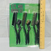 Front view of unopened 6 pc wire brush set showing plastic handles and wire bristles in original packaging with ruler for scale.