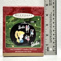 Front view of the Hallmark Keepsake Ornament box showing the 1962 Barbie Hatbox Doll Case design on the ornament with ruler for size reference.