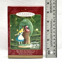 Original box of Hallmark Keepsake ornament featuring Alice meeting the Cheshire Cat with a ruler showing approximate height of the box approximately 6 inches.