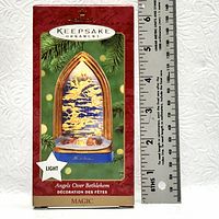 Photo of the Hallmark Keepsake Ornament packaging showing the 'Angels Over Bethlehem' light-up ornament inside a gothic window shaped frame with angels and Bethlehem scene.