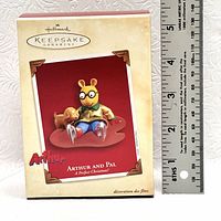 Photo of the Hallmark Keepsake Ornament box with image of Arthur and Pal ornament on front and a ruler for size reference.