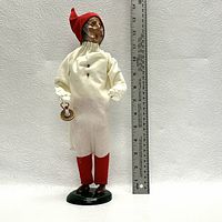 Front view of the Byers' Choice figurine depicting Scrooge, with a ruler showing height scale approximately 12 inches tall, wearing a white nightshirt, red nightcap, and holding a candle holder.