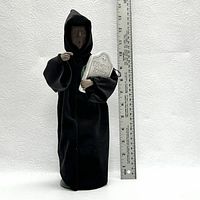 Front view of the black hooded figurine holding 'Ebenezer Scrooge' gravestone next to a ruler for size reference (approx 12 inches).