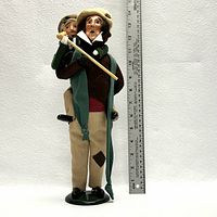 Front view of Bob Cratchit carrying Tiny Tim figurine standing next to a ruler for size reference.