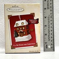 Box of Hallmark Keepsake ornament showing front image, branding, and feature highlights alongside a ruler for size reference.