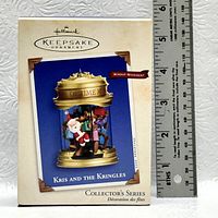 Photo of the Hallmark Keepsake Ornament's original box showing the Kris and the Kringles Windup Movement Collector's Series with a ruler for scale.