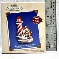 Photo of Hallmark Keepsake Ornament box with lighthouse design and flashing light badge, includes visible ruler for scale.
