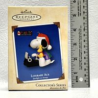 Photo showing the original box of the Hallmark Keepsake Ornament featuring Snoopy as the Literary Ace, with a ruler for size reference.