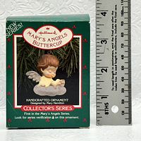 Photo of the original box packaging for the handcrafted ornament, showing branding, series information, and scale with a ruler.