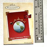 Photo of the Hallmark Keepsake Ornament box showing the 'Merry Christmas, World!' ornament with sound and light features and a ruler for size reference.