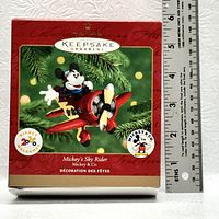 Photo of the closed box of the Hallmark Keepsake Ornament 'Mickey's Sky Rider' with a ruler showing height around 5 inches