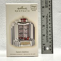 Photo of Hallmark Keepsake Santa's Jukebox ornament in original box with ruler indicating size approximately 4 inches tall.
