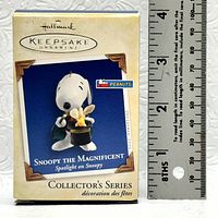 Photo of the Hallmark Keepsake Ornament box featuring Snoopy the Magnificent with a ruler for size reference.