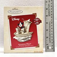 Photo of the front of the packaging showing the Steamboat Willie ornament with ruler for size reference.